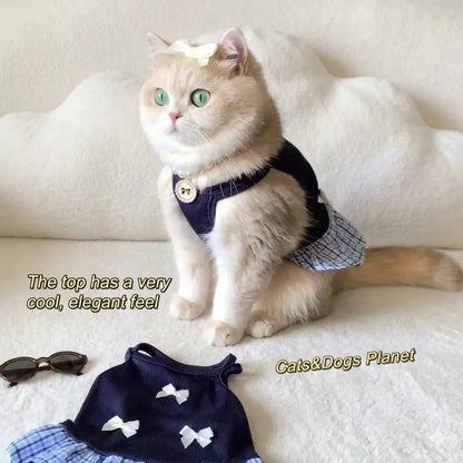 A chic, green-eyed cat sitting elegantly wearing a full "Old Money" style outfit set including a navy blue bow dress and a pearl necklace, conveying a sophisticated and "cool" aesthetic in a minimalist cloud-white interior.