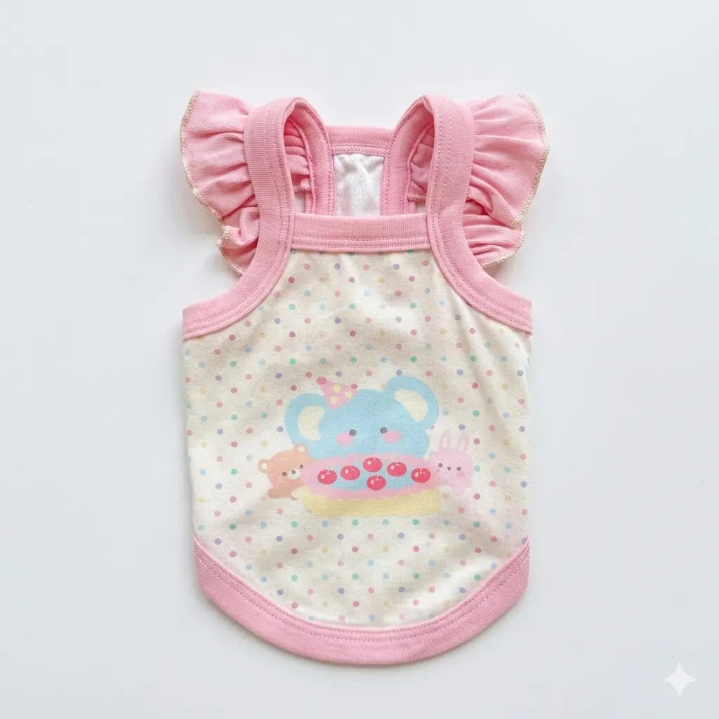 Small white Bichon puppy wearing a macaron pink cartoon camisole for a summer outing.