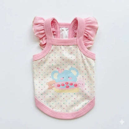 Small white Bichon puppy wearing a macaron pink cartoon camisole for a summer outing.