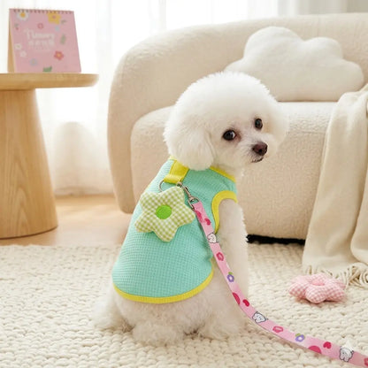 Hand holding a green dog harness set with a pearl hanger and cartoon printed leash.